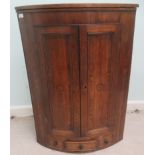 A George III oak and mahogany quadrant corner cabinet with a pair of panelled doors, over a