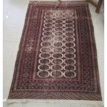 A Bokhara rug with three columns of thirteen guls, bordered by stylised designs, on a red ground