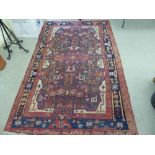 A Persian rug, decorated with repeating stylised designs, on a multi-coloured ground  62" x 100"