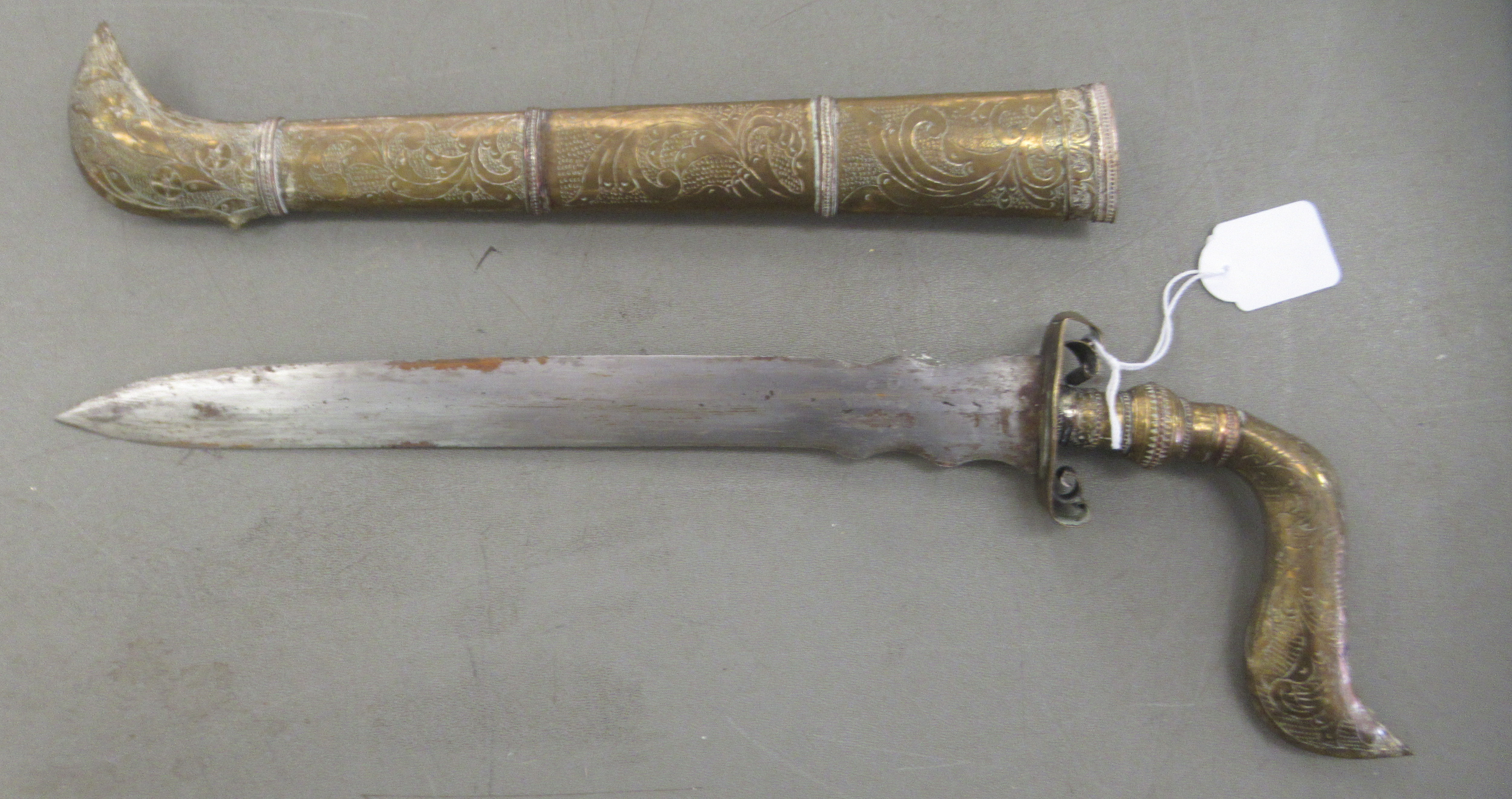 An Indo-Persian dagger with an engraved brass handle, scrolled guard and straight, part wavy edged