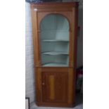 A 20thC pine standing corner cabinet with three open shelves, over a panelled door, on a plinth