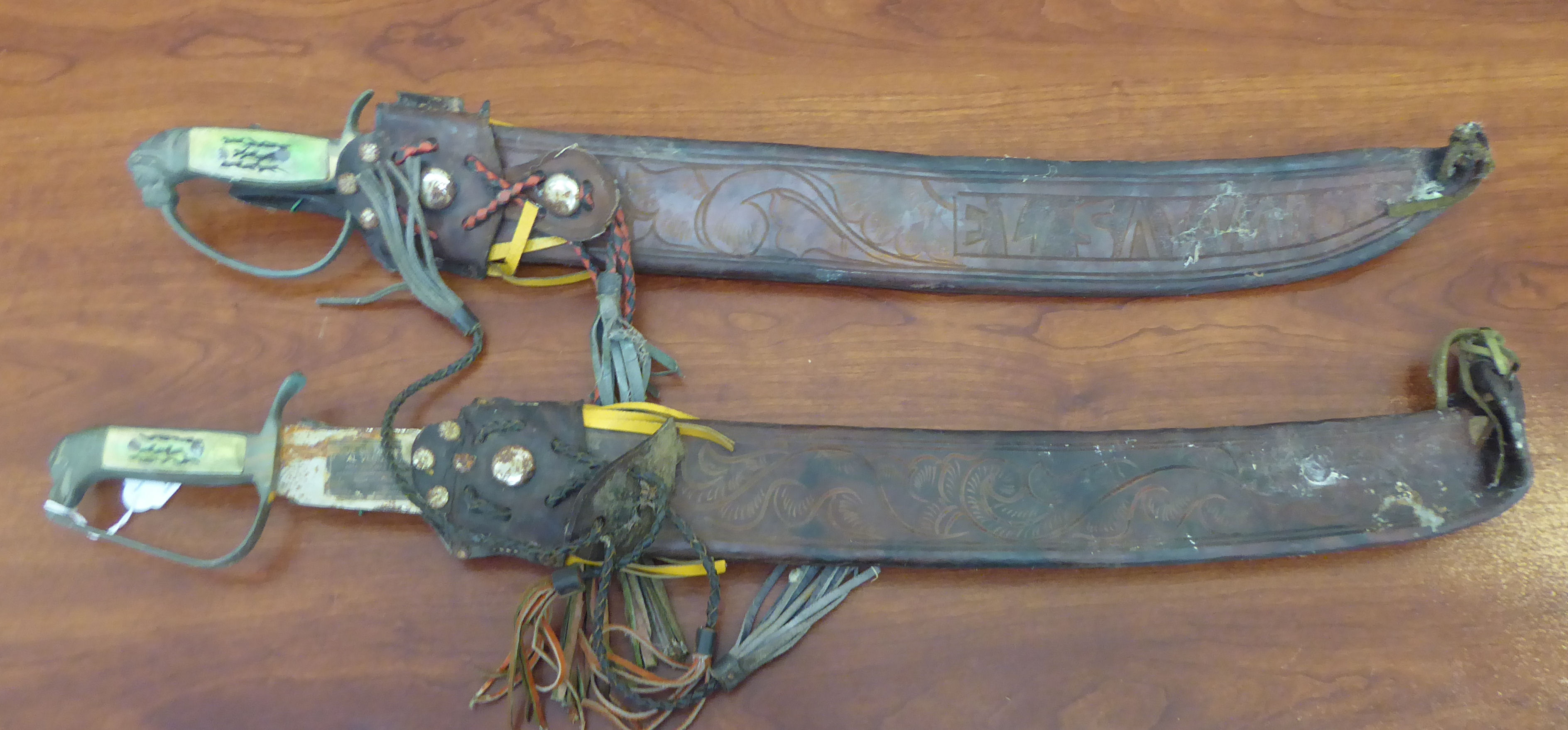 Two Corona Prodotto machetes, each with a hide sheath