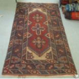 A Persian rug, decorated with two central hexagonal motifs, bordered by stylised designs, on multi-