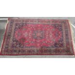 A Persian carpet, decorated with a central stylised starburst motif, bordered by floral designs,