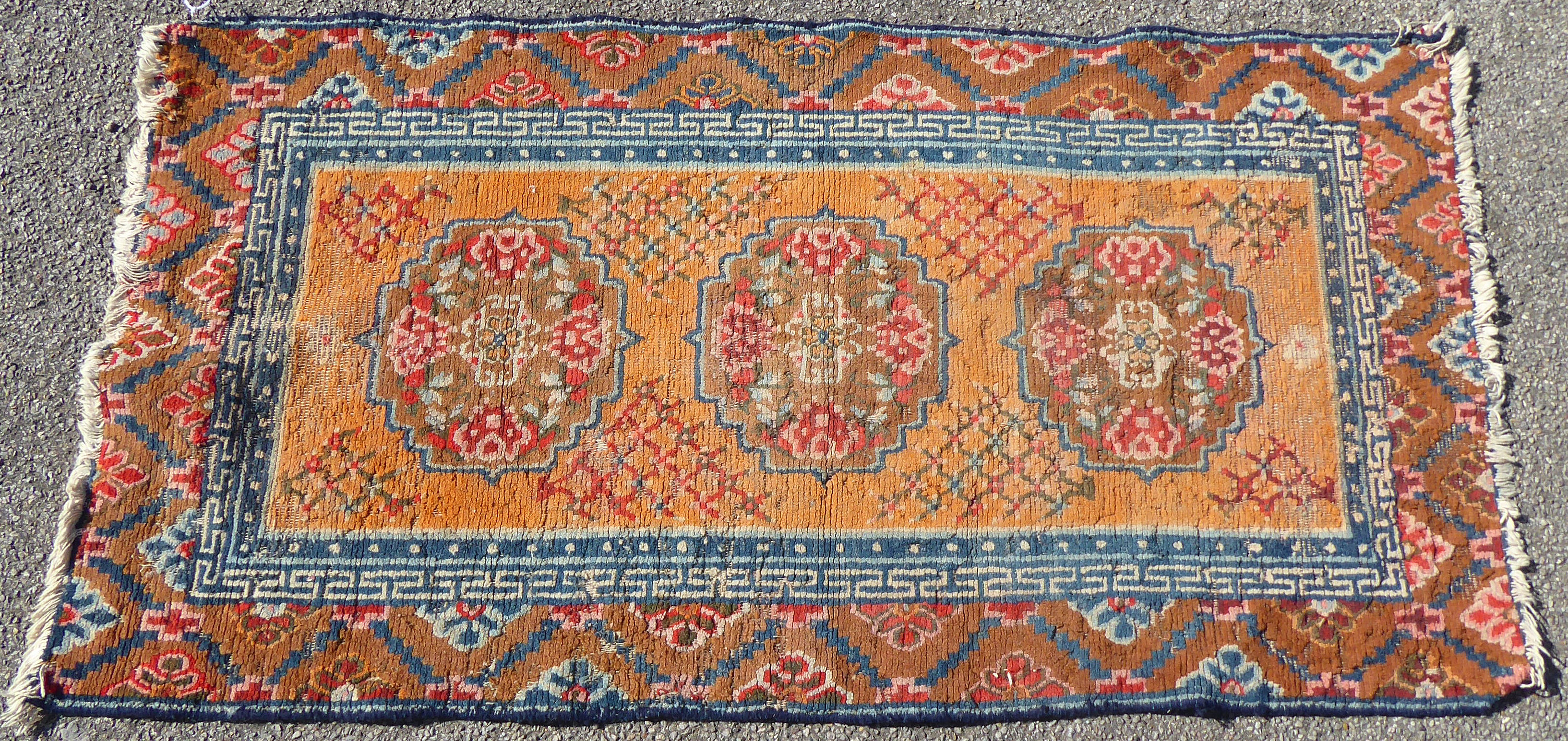 A 19thC Chinese Ning Zia rug with three medallions on a caramel coloured ground  54" x 29"