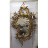 A late 18th/early 19thC mirror, set in a carved giltwood, foliate scrolled and floral, rococo