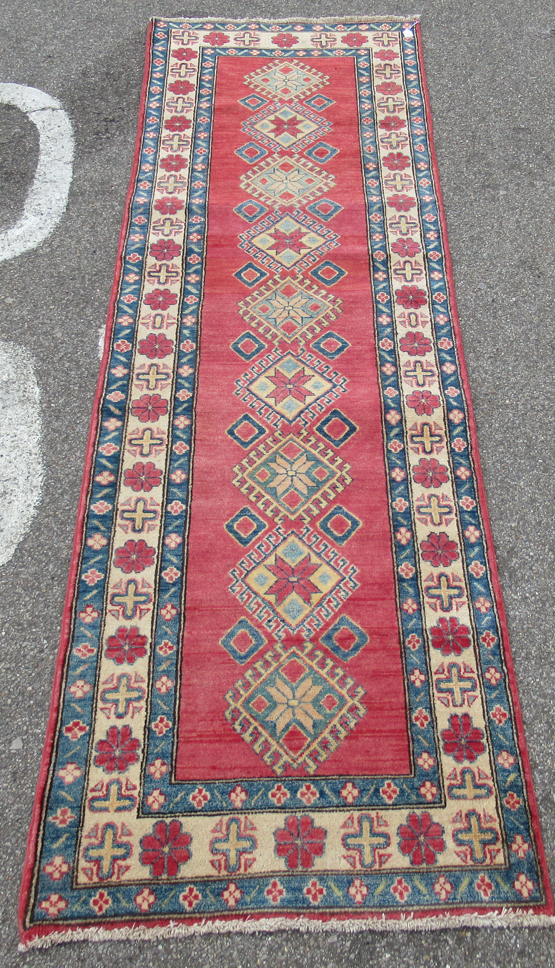 A Persian runner, decorated with repeating central diamond formations, bordered by stylised designs,