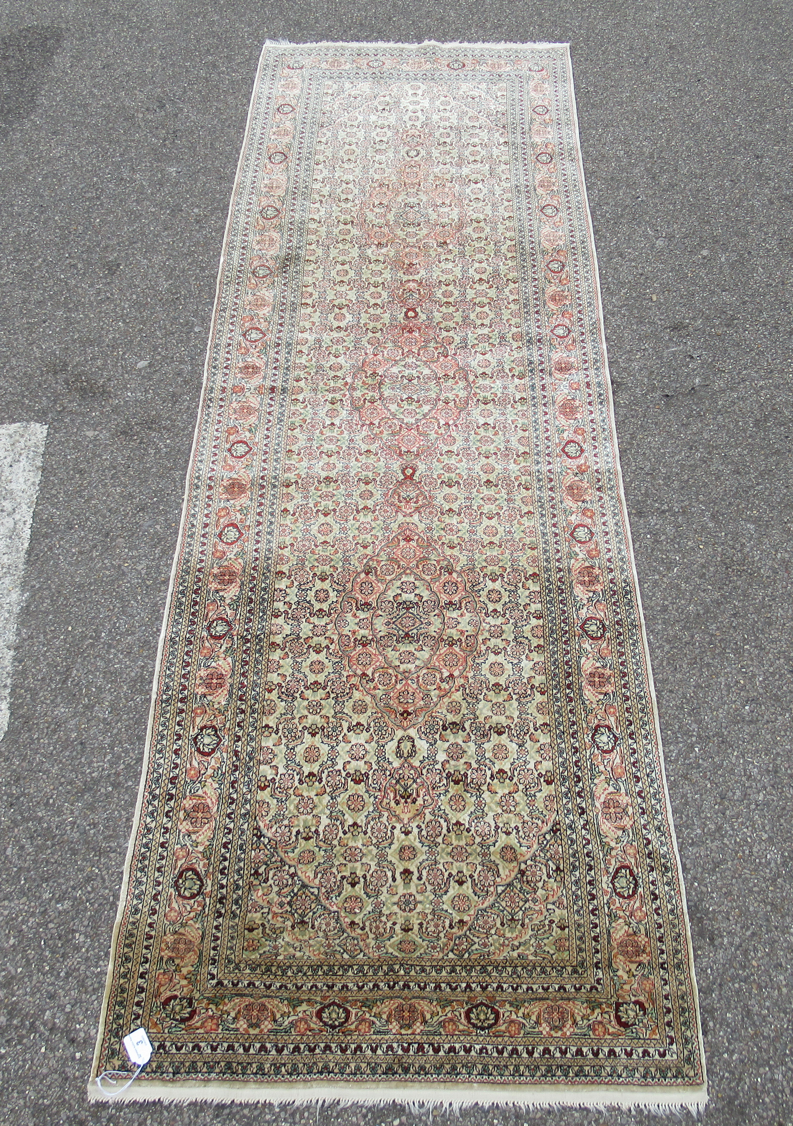 A Herke silk runner, profusely decorated in repeating floral and stylised designs, on a multi-