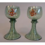 A pair of antique Roemer pale green glass wines, the cup shape bowls with enamelled coats of arms,