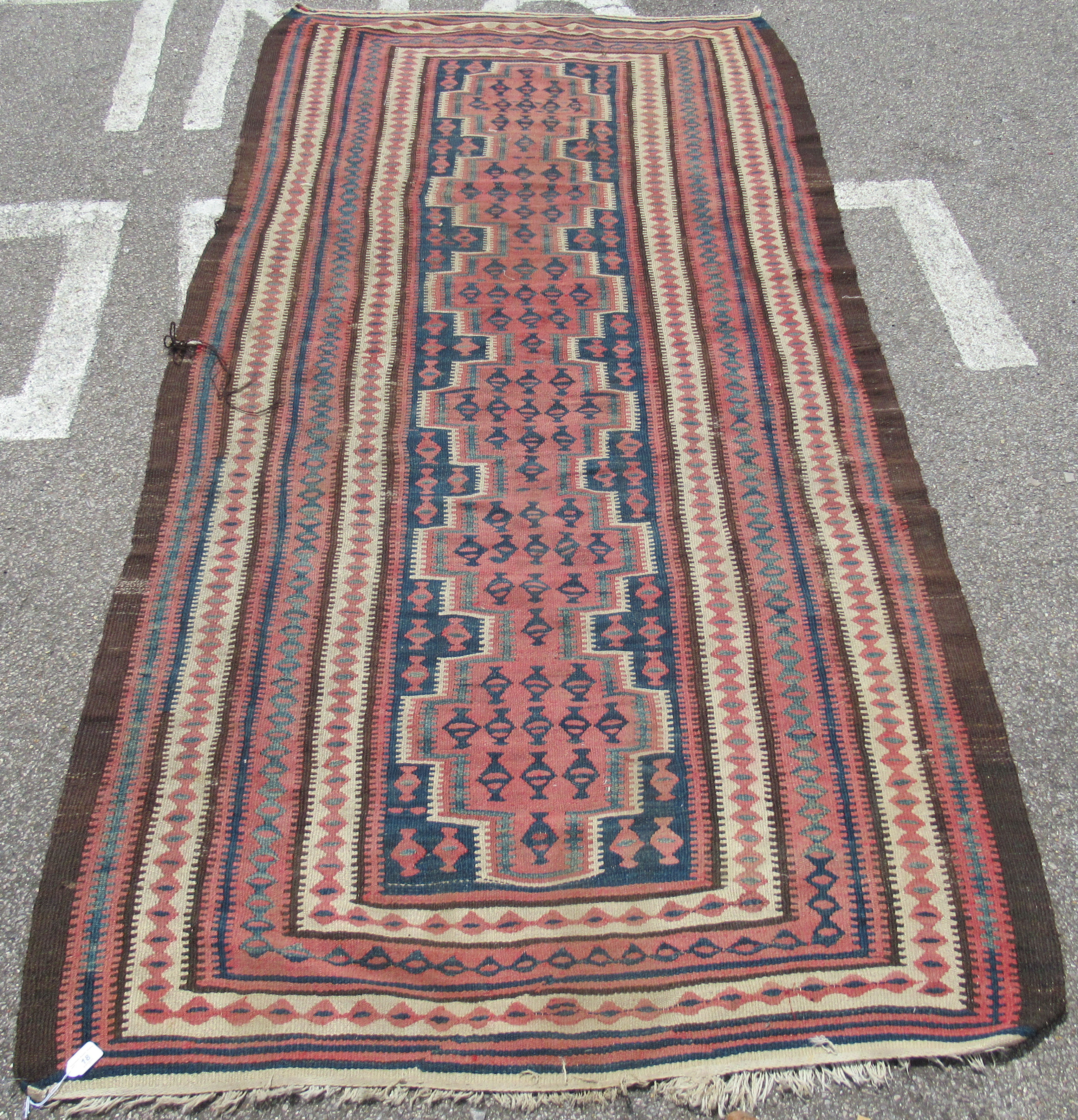 A Turkish Kelim rug, decorated with repeating geometric and other designs, on a brown ground  54"