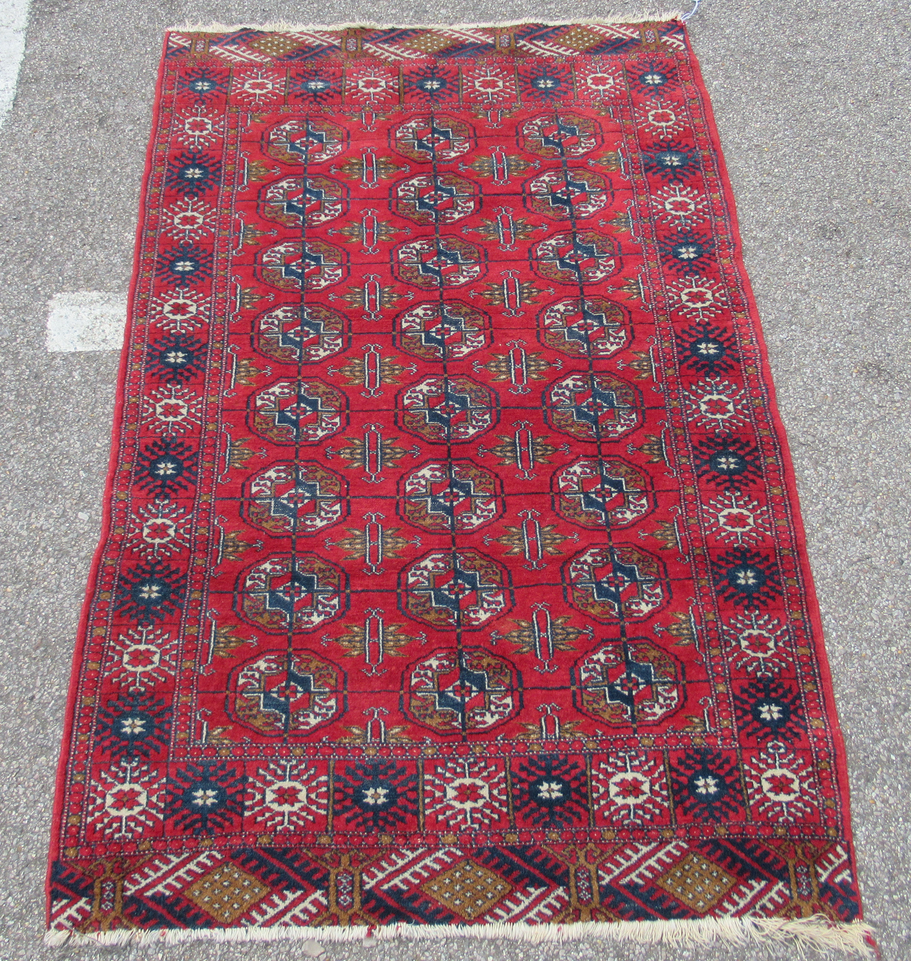 A Bokhara rug, decorated with three columns of eight octagonal guls, bordered by stylised designs,