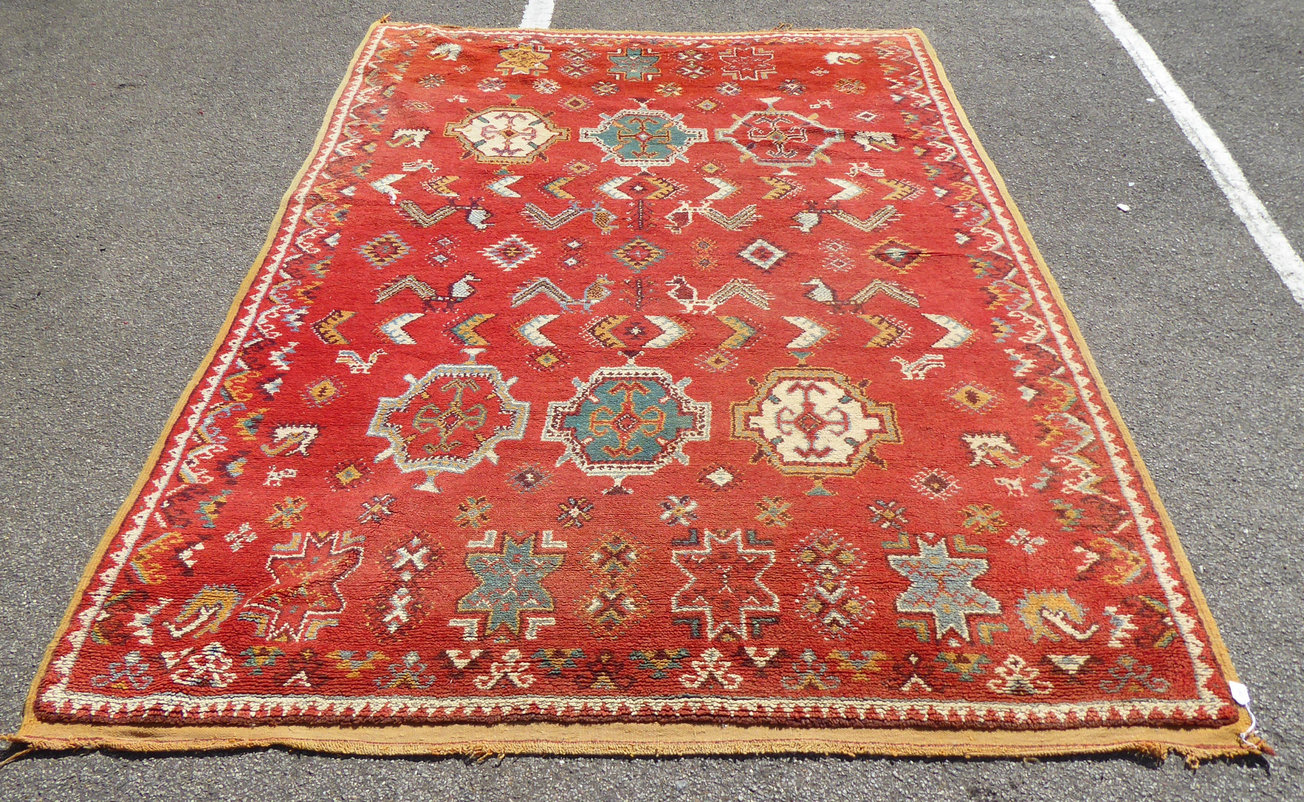 A mid 20thC Turkish carpet with birds and geometric motifs on a red ground  115" x 82"
