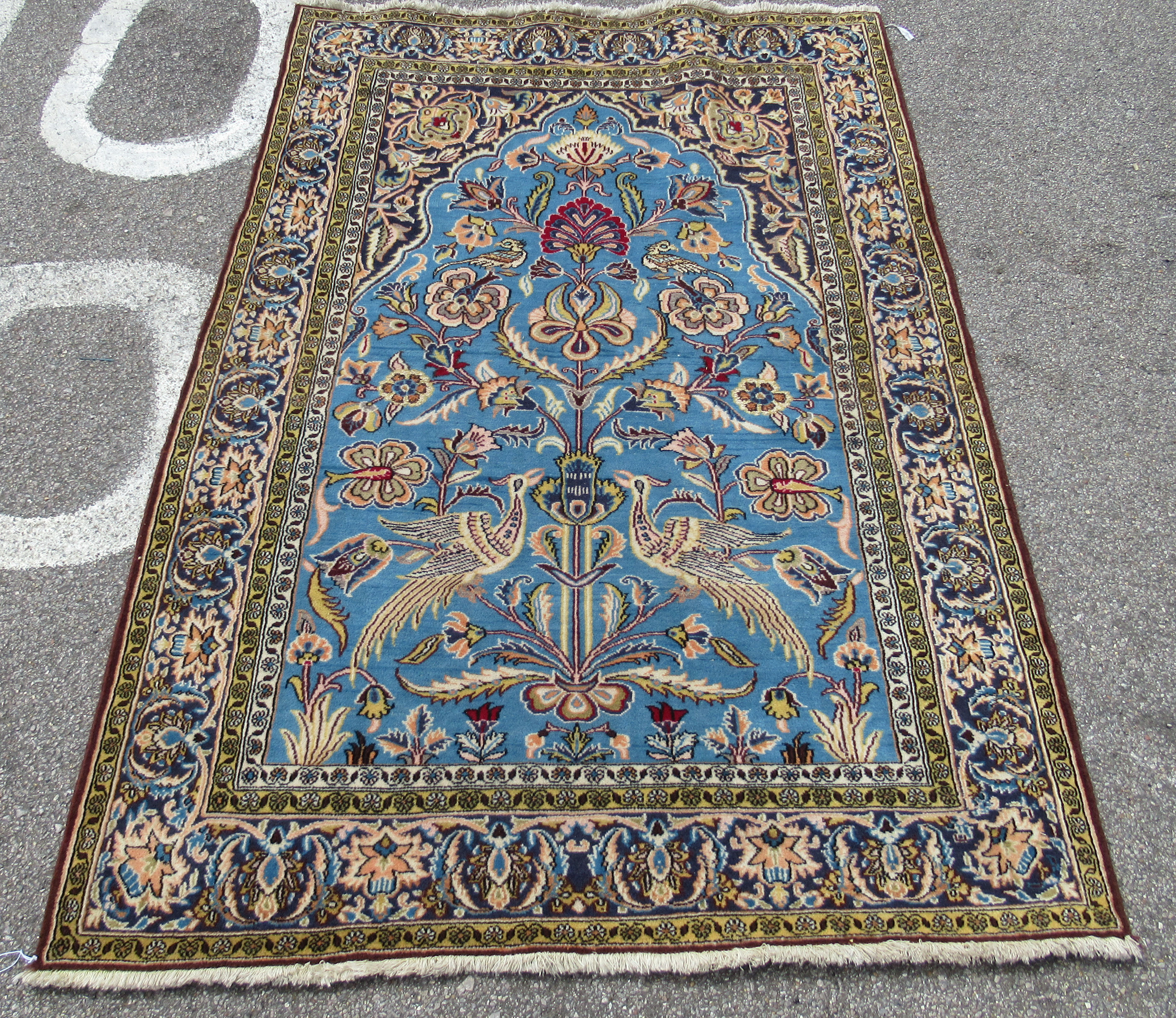 A Persian rug, decorated with exotic birds, flora and foliage, on a blue and multi-coloured