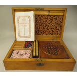 An early 20thC satin pine games compendium, the lockable hinged lid enclosing a fitted interior, for