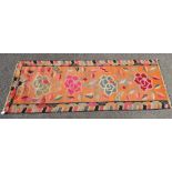 A 1920s Chinese Art Deco runner with bold floral motifs on a coral coloured ground  85" x 31"