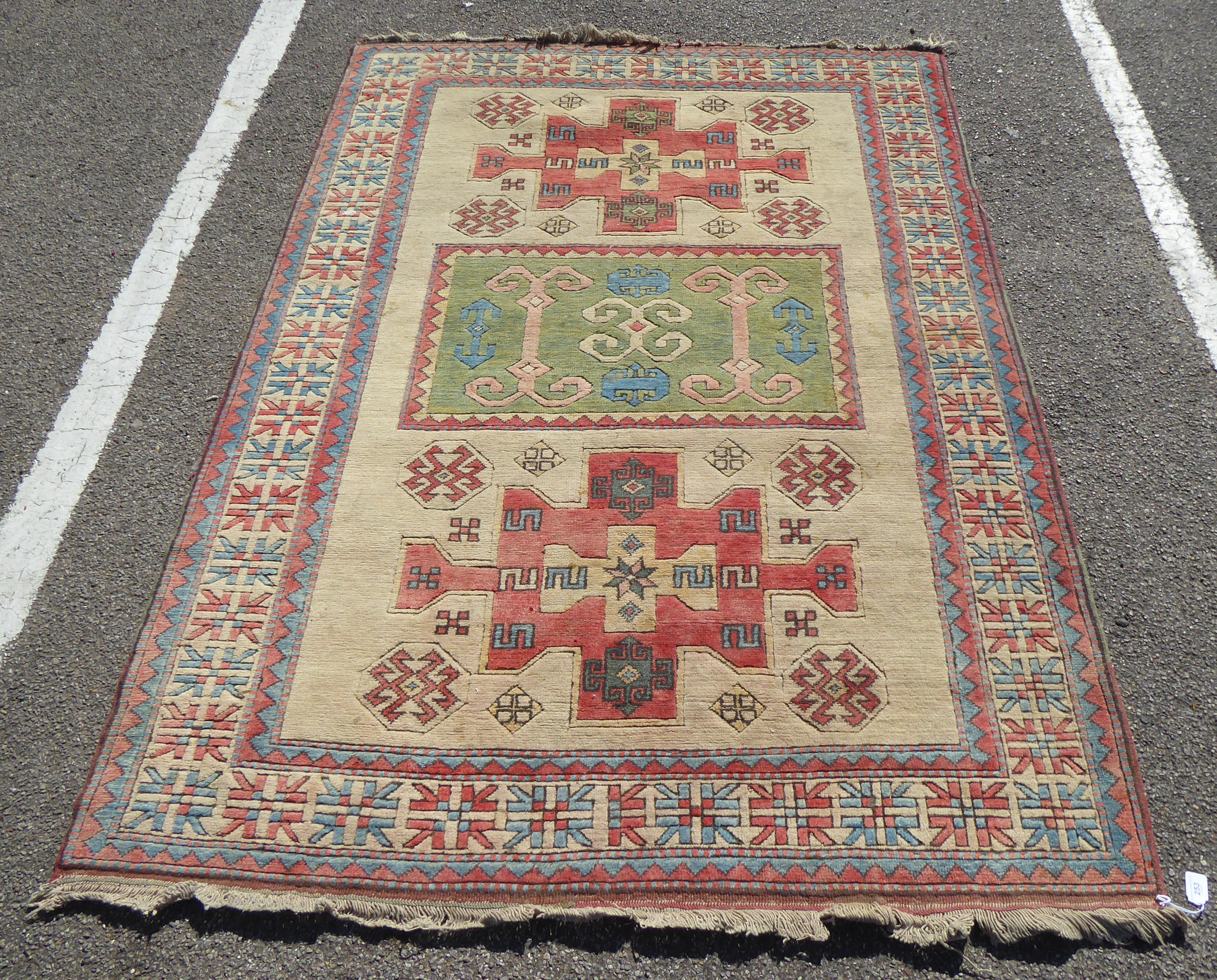 A Kazak style Caucasian rug with geometric motifs on a cream coloured ground  86" x 60"