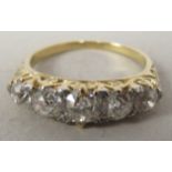 A gold coloured metal five stone diamond ring, in a decoratively scrolled setting