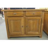 A modern light oak sideboard with two frieze drawers, over a pair of panelled doors, raised on