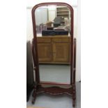 A Victorian style mahogany framed cheval mirror, the bevelled, arched plate pivoting on horns,