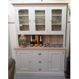 A modern cream painted light oak dresser, the superstructure with three glazed doors, the base