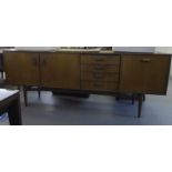 A 1970s G-Plan teak sideboard with moulded grab handles, comprising a pair of cupboard doors, a bank