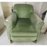 An early 20thC green fabric upholstered, enclosed armchair, raised on turned forelegs and casters