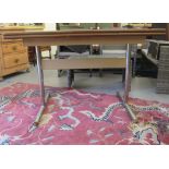 A 1950s/1960s dining table with a laminated top, raised on a chromium plated trestle design base