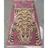 An Oriental themed washed woollen rug, fashioned as a tiger skin, on a pink ground  37" x 73"