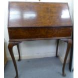 A 1930s walnut finished clerks bureau. the fall flap enclosing a part fitted interior, raised on