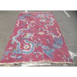 An Oriental themed washed woollen rug, decorated with exotic birds and dragons, on a plink ground