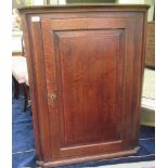 A 19thC oak hanging corner cupboard with canted sides, enclosed by a full height, fielded panel door