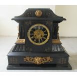 An early 20thC slate cased mantel clock of architectural form with neo-classical ornament, on a