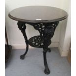 An early 20thC black painted cast iron pub table with mask ornament and a turned stained oak top