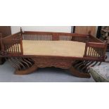 An Asian teak daybed with a low, spindled gallery and mattress, on a solid base and cushion,
