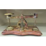 Edwardian lacquered brass desktop balance type postal scales, on a serpentine front, mahogany plinth