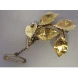 An 18ct gold leaf design brooch, set with a diamond