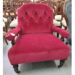 An early 20thC part button red fabric upholstered salon chair with open arms, raised on turned