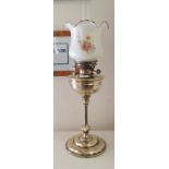 An Edwardian lacquered brass lamp with a later glass shade, on a tapered column and stepped circular