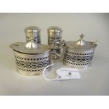 An Edwardian four piece silver condiments set with decoratively pierced sides and blue glass liners