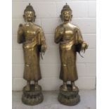 A pair of 20thC bronze Buddhist figures wearing traditional costume, each standing on a lotus leaf