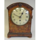 A William IV inlaid brass and carved mahogany cased bracket timepiece with a low, round arch top, on
