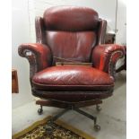 A 20thC desk chair, stud upholstered in ox blood coloured hide, on a swivel base, splayed legs and