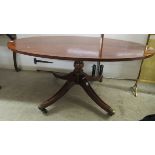 A reproduction mahogany finished oval coffee table, raised on splayed legs with brass capped casters