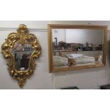 A 20thC mirror, the shaped plate set in a foliate scrolled gilt frame  26" x 15"; and a bevelled