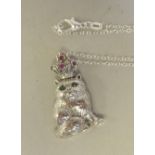 A silver coloured metal novelty pendant, a seated cat with ruby eyes, wearing a crown, on a fine
