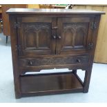 A mid 20thC Jacobean style carved oak cabinet, the pair of doors over a shallow drawer and open