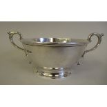 A silver shallow bowl with an applied wire rim and opposing double C-scrolled handles, on a