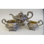 A matched silver three piece tea set, comprising a pear shaped teapot with a scrolled handle,