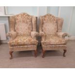 A pair of mid 20thC Queen Anne style wingback chairs with scrolled arms, upholstered in cream and