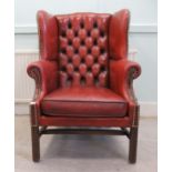 A mid 20thC library wingback enclosed armchair, part stud and button upholstered in oxblood coloured